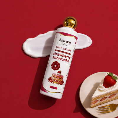 Brown Butters Strawberry Shortcake Body Lotion bottle on a pink cream splash over red, with a cake slice