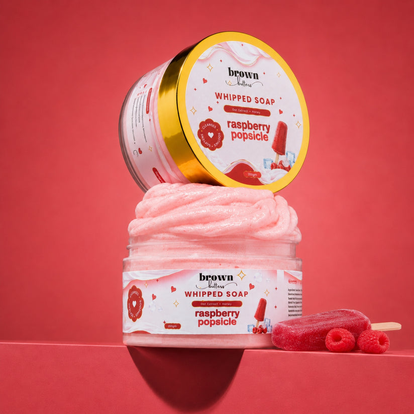 Brown Butters Raspberry Popsicle Whipped Soap in a clear jar with lid propped above and raspberries on pink