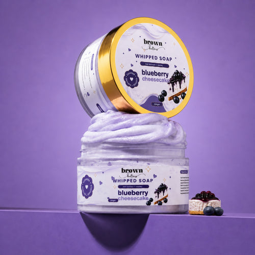 Brown Butters Blueberry Cheesecake Whipped Soap swirled in a clear jar with its lid and a dessert prop on purple