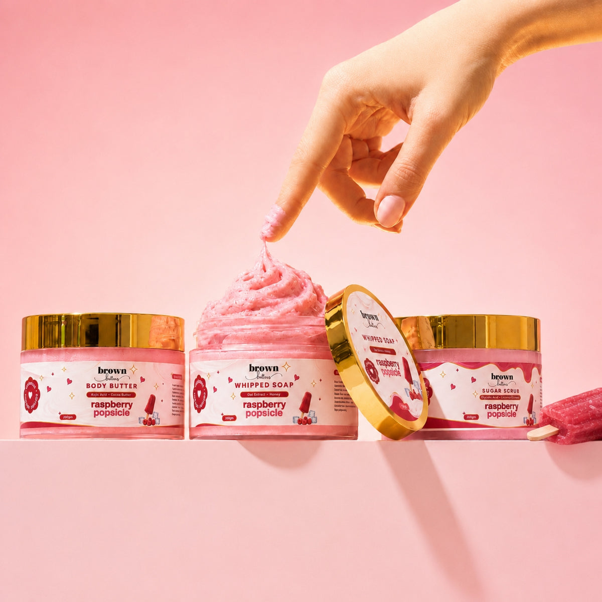 Brown Butters Raspberry Popsicle Dessert Spa Trio on pink, a popsicle stick dipped in the whipped soap.