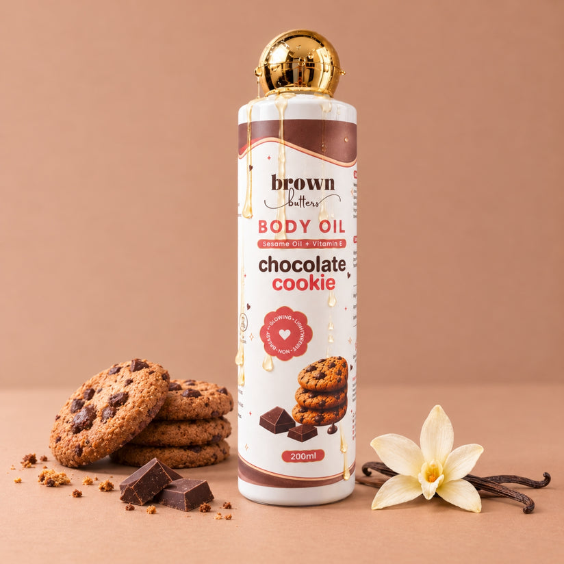 Brown Butters Chocolate Cookie Body Oil bottle with gold cap on beige, with cookies, dark chocolate and vanilla
