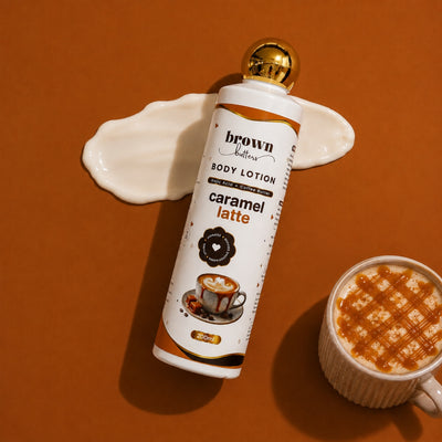 Brown Butters Caramel Latte Body Lotion bottle on warm brown with a cream smear and a caramel drizzled latte