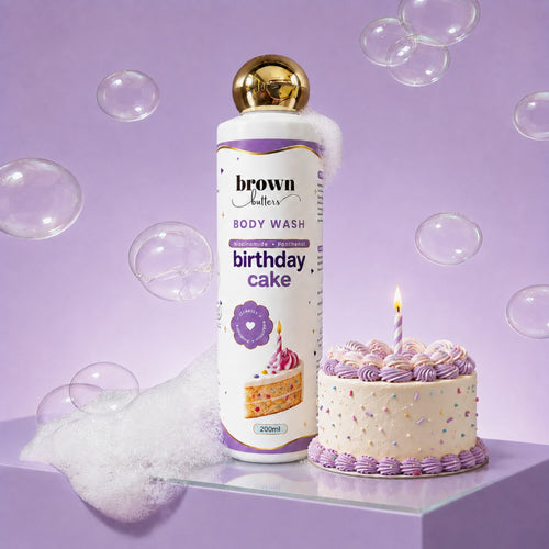 Brown Butters Birthday Cake Body Wash bottle on a purple pedestal with a candlelit cake, bubbles and foam
