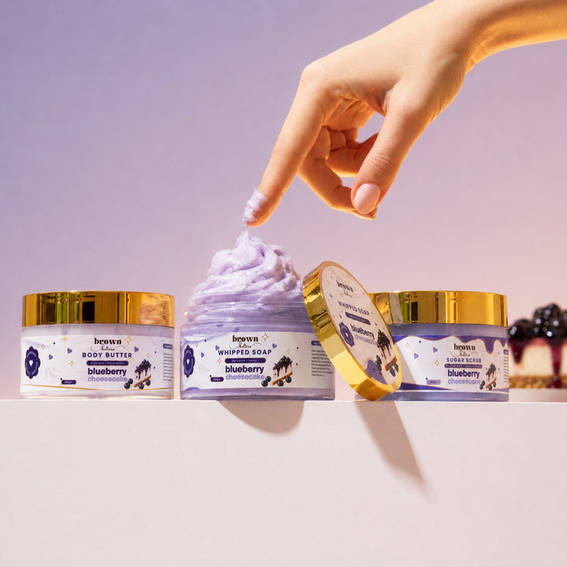 Brown Butters Blueberry Cheesecake Dessert Spa Trio jars with gold lids, a finger in the whipped soap.