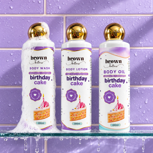 Brown Butters Birthday Cake Body Wash, Lotion and Oil bottles on a wet purple tiled shelf