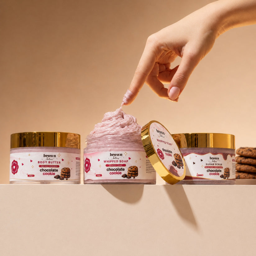 Brown Butters Chocolate Cookie Dessert Spa Trio on beige, a hand touching the pink whipped soap jar.