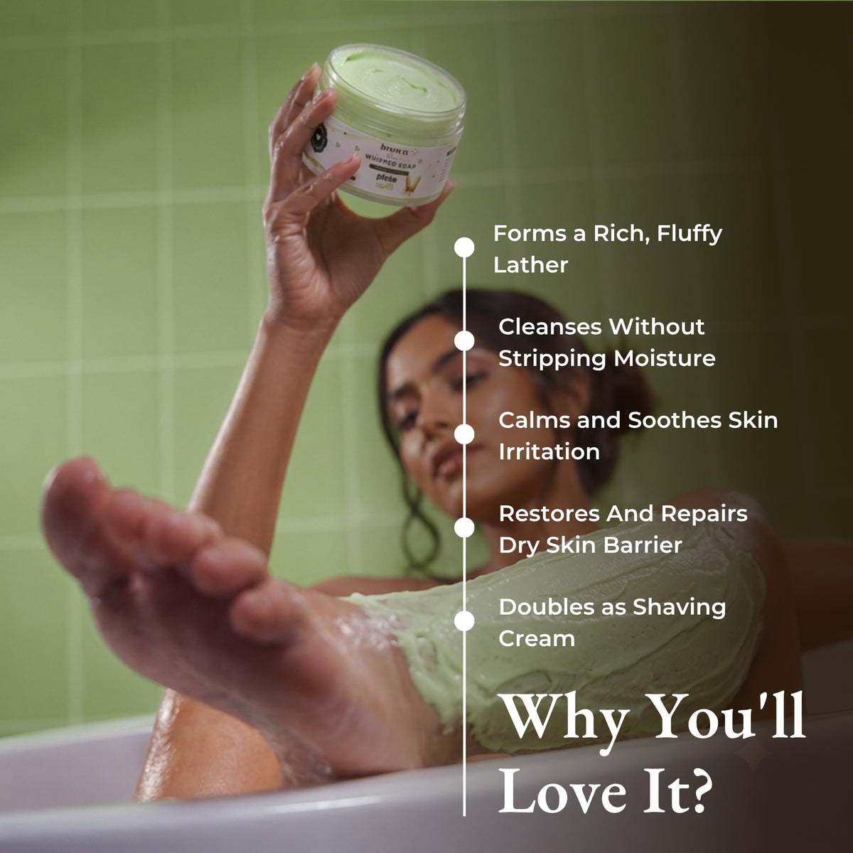 Brown Butters Pista Kulfi Whipped Soap held in a bathtub in a green tiled bathroom with a benefits overlay