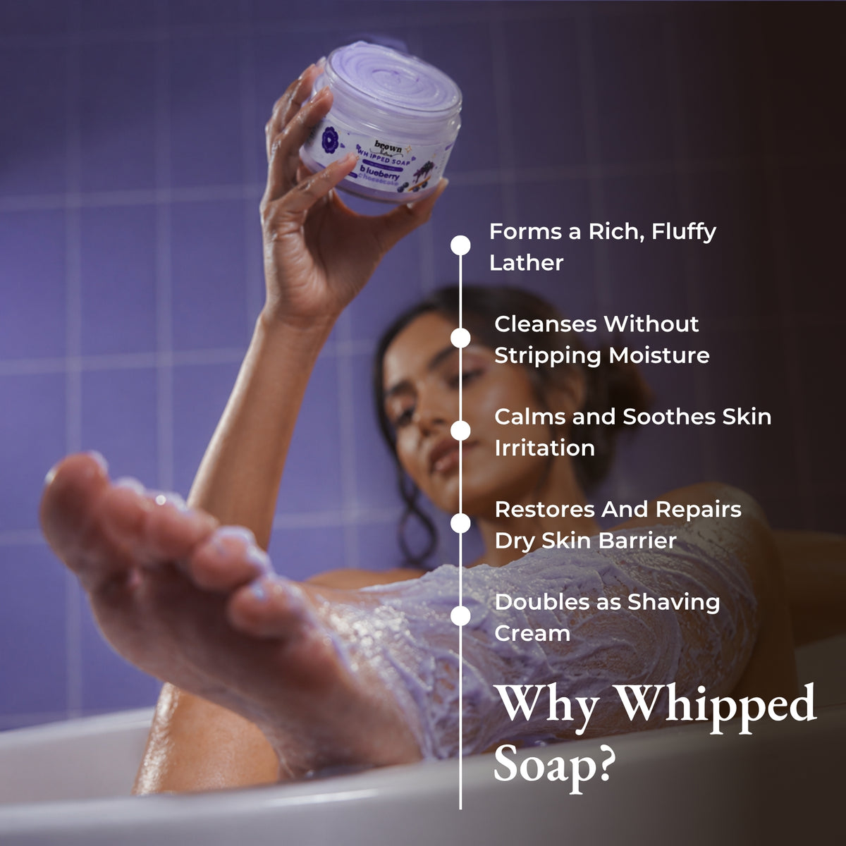 Brown Butters Blueberry Cheesecake whipped soap held in a purple tiled bath, with lather benefits listed.